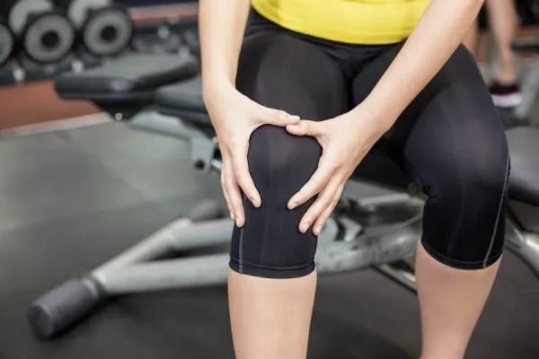 woman holding knee at the gym